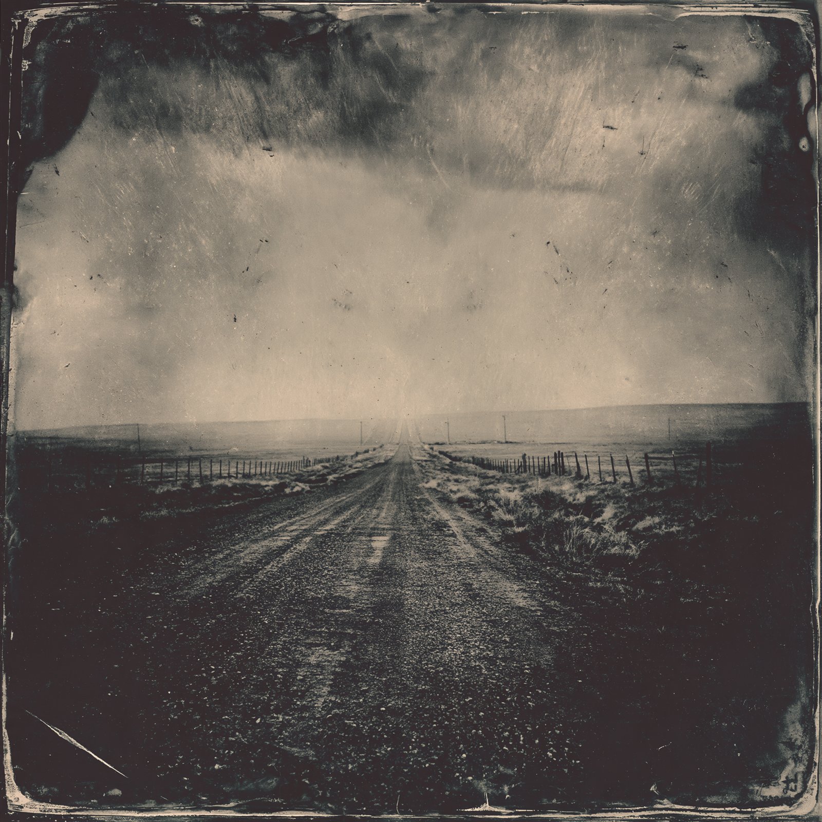 A dirt road running straight to a flat prairie horizon
